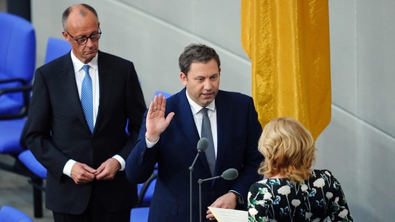 Lars Klingbeil (m, SPD), Bundesminister der Finanzen und Vizekanzler, legt im Beisein von Bundeskanzler Friedrich Merz (l, CDU) vor Bundestagspräsidentin Julia Klöckner (CDU) im Bundestag bei der Vereidigung den Amtseid ab. © dpa Foto: Kay Nietfeld