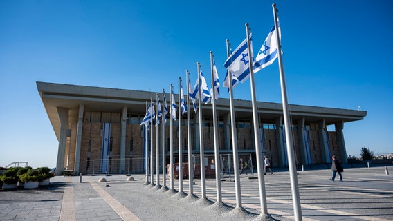Israelische Fahnen wehen vor der Knesset, dem Einkammerparlament des Staates Israel. © Christophe Gateau/dpa 