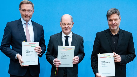 Christian Lindner, (l-r, FDP), Olaf Scholz (SPD) und Robert Habeck (Grüne) präsentieren den unterzeichneten Koalitionsvertrag zur Bildung einer Bundesregierung. © dpa Foto: Bernd von Jutrczenka