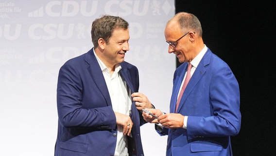 CDU-Vorsitzender und -Kanzlerkandidat Friedrich Merz (r) und der SPD-Vorsitzende und designierte Vizekanzler Lars Klingbeil unterhalten sich im Euref-Campus nach der Unterzeichnung des Koalitionsvertrags. © Michael Kappeler/dpa 