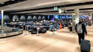 Auf dem Bild sind Reisende zu sehen, die ihre Koffer zu suchen. © NDR Foto: Privat