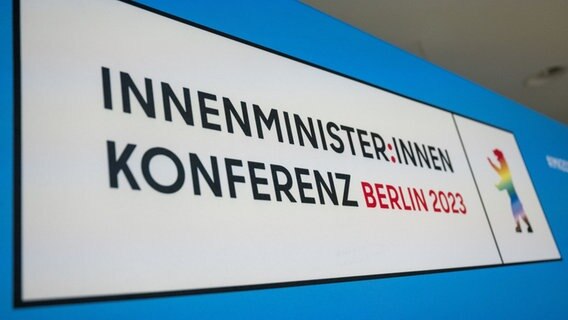 Bei der Innenministerkonferenz (IMK) steht ein Hinweisschild mit der Aufschrift "Innenminister:innen Konferenz Berlin 2023". © dpa-Bildfunk Foto: Christophe Gateau/dpa
