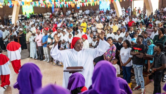 Eine katholische Gemeinde in der Republik Kongo feiert einen Gottesdienst, in der Mitte steht eine Frau im weißen Gewand © AP/dpa Foto: Moses Sawasawa