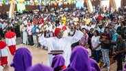 Eine katholische Gemeinde in der Republik Kongo feiert einen Gottesdienst, in der Mitte steht eine Frau im weißen Gewand © AP/dpa Foto: Moses Sawasawa