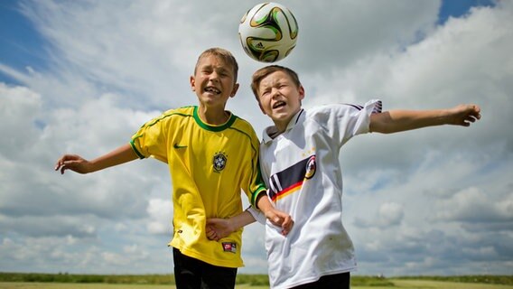 Zwei Kinder springen beim Fußballspielen zu einem Kopfballduell in die Luft. © dpa picture alliance Foto: Julian Stratenschulte