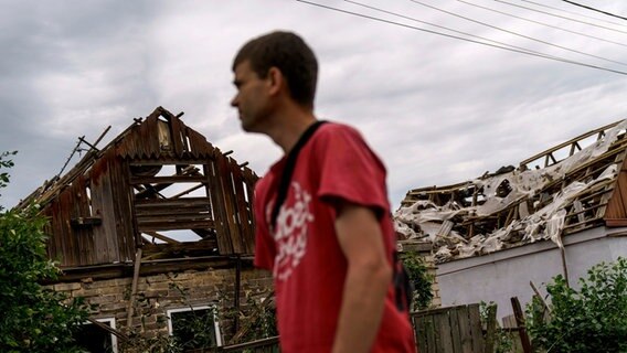 Ein Fußgänger geht in Kramatorsk an beschädigten Häusern vorbei. © David Goldman/AP/dpa 