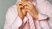 Ein Mann bindet sich eine Krawatte. © dpa Foto: dpa