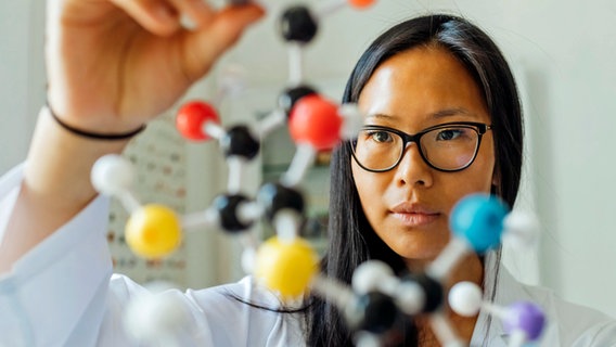 Eine junge Wissenschaftlerin betrachtet ein DNA-Modell im Labor. © picture alliance / Westend61 | Eugenio Marongiu 