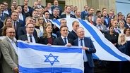 Mitglieder des Niedersächsischen Landtags stehen auf einer Treppe und halten israelische Flaggen in den Händen. © dpa bildfunk Foto: Julian Stratenschulte