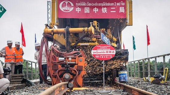 Chinesische Eisenbahnarbeiter bei Schienenarbeiten an einer Strecke in Laos. © picture alliance Foto: Xinhua News Agency