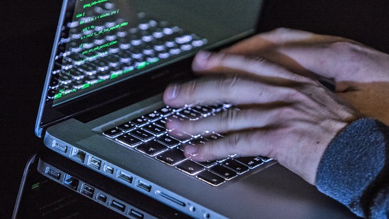 Zwei Hände schreiben auf der Tastatur eines Laptops, auf dem dunklen Bildschirm sind grüne Buchstaben und Zahlen zu erkennen. © dpa picture alliance Foto: Silas Stein