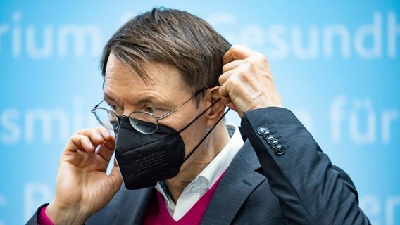 Gesundheitsminister Karl Lauterbach setzt eine schwarze FFP2-Maske auf. © IMAGO / Emmanuele Contini 