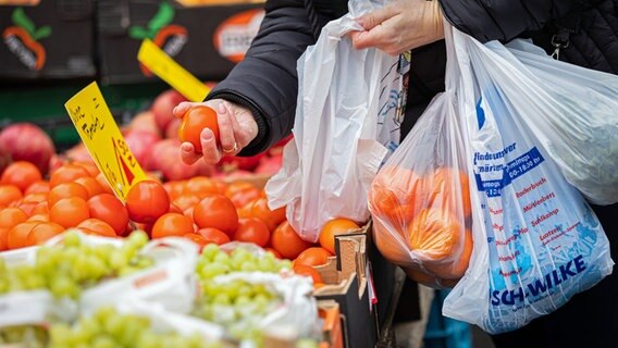 Eine Kundin begutachtet eine Tomate an einem Stand auf einem Wochenmarkt in Hannover. © dpa-Bildfunk 