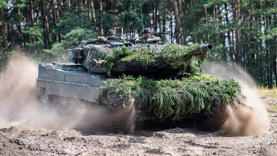 Mit Tannenzweigen getarnter Kampfpanzer vom Typ Leopard 2 A6 fährt durch ein Waldstück © dpa-Bildfunk Foto: Guido Kirchner/dpa