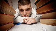 Junger Mann schaut müde auf ein Blatt Papier © Fotolia.com Foto: vladans