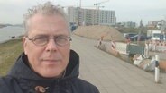 NDR-Reporter Nicolas Lieven steht vor einer Baustelle in der Hamburger Hafencity. © NDR Info 