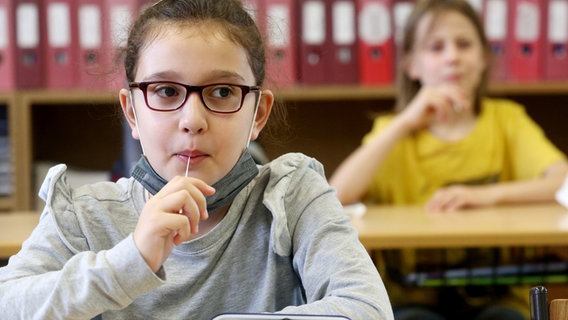 Ein Mädchen macht in einer Grundschule einen Lolli-Test. © picture alliance/dpa | Roland Weihrauch 