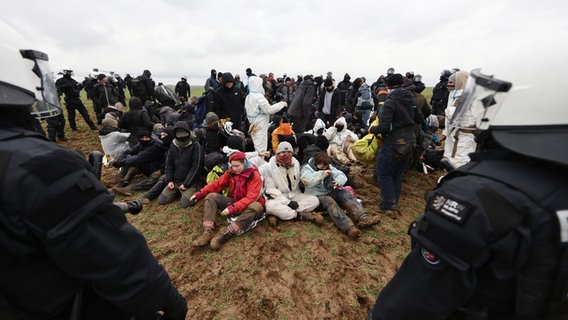 Polizisten und Klimaaktivisten stehen auf einem Feld nahe der Abrisskante von Garzweiler II. © Rolf Vennenbernd/dpa 