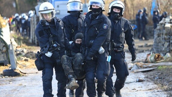 Polizisten tragen einen Klimaaktivisten vom besetzten Braunkohleort Lützerath weg. © Oliver Berg/dpa 