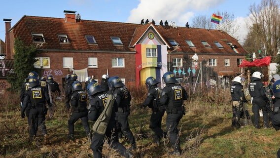 Klimaaktivisten sitzen im besetzten Braunkohleort Lützerath auf einem Hausdach. © Oliver Berg/dpa 