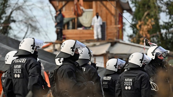 Eine Gruppe Polizisten steht bei der Räumung von Lützerath vor Bretterhütten, die von Aktivisten und Demonstranten gebaut worden waren. © dpa bildfunk Foto: Federico Gambarini