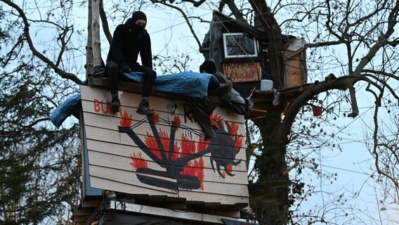 Klimaaktivist sitzt auf einem Haus auf Stelzen © Federico Gambarini/dpa 