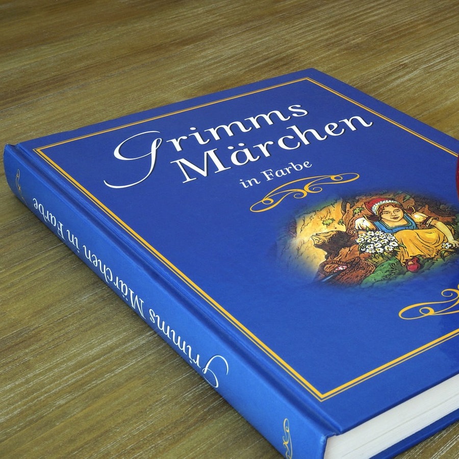 Ein Apfel liegt auf einem blauen Märchenbuch mit dem Namen "Grimms Märchen in Farbe". © picture alliance/ZB Foto: Sascha Steinach