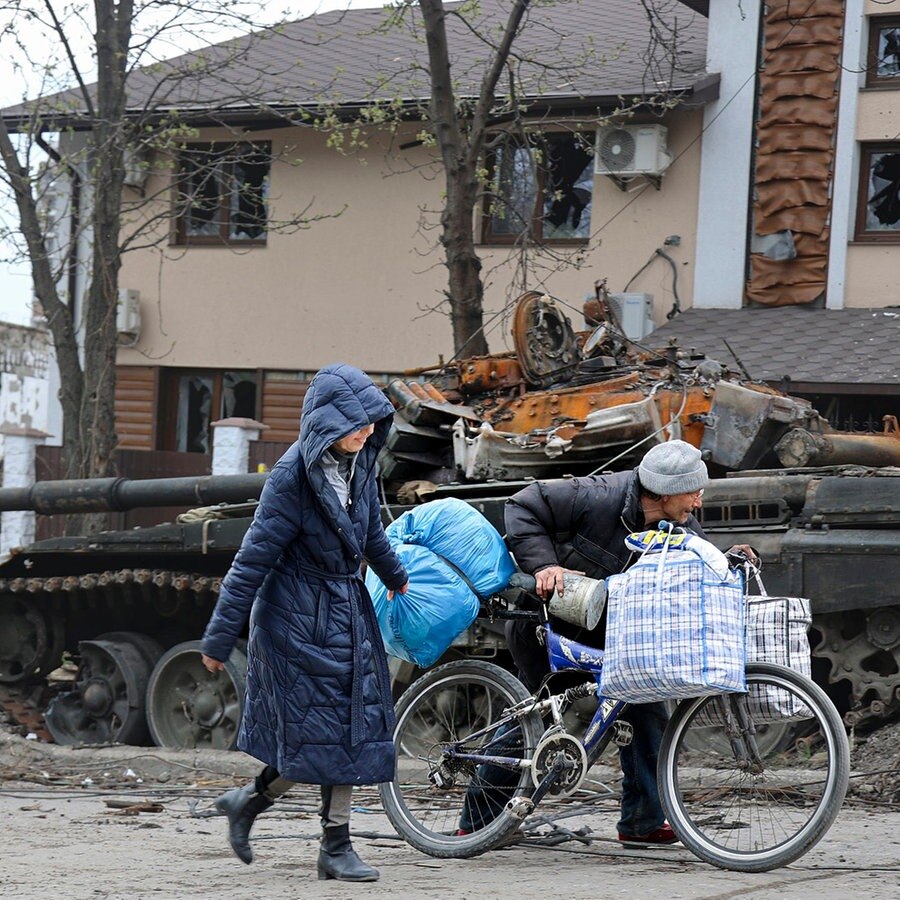 Zivilisten gehen an einem Panzer vorbei, der bei schweren Kämpfen in einem von den von Russland unterstützten Separatisten kontrollierten Gebiet in Mariupol zerstört wurde.  