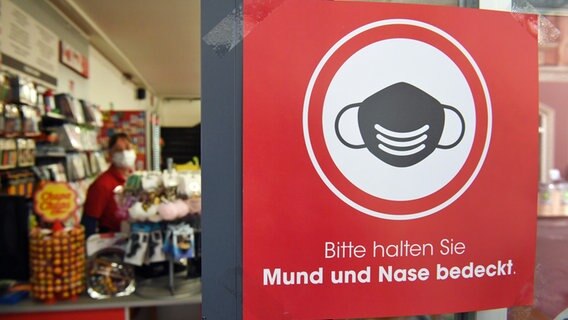 Ein Schild mit dem Schriftzug "Bitte halten Sie Mund und Nase bedeckt." hängt an einem Geschäft in der Ladenstraße von Stralsund. © dpa-Bildfunk Foto: Stefan Sauer