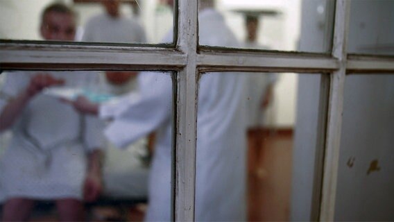 Una vista desde la ventana donde un hombre toma su medicación en un hospital psiquiátrico.  © NDR 