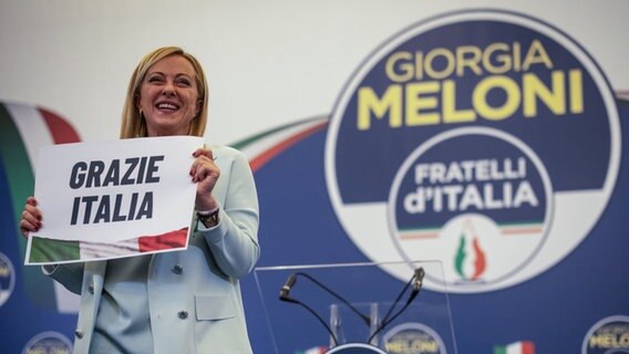 Giorgia Meloni hält ein Schild mit der Aufschrift "Grazie Italia" während einer Pressekonferenz in der Wahlkampfzentrale ihrer Partei. © dpa Foto: Oliver Weiken