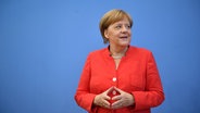 Angela Merkel bei ihrer Sommerpresse-Konferenz, die trägt ein Rotes Jacket. © dpa-Bildfunk Foto: Bernd Von Jutrczenka