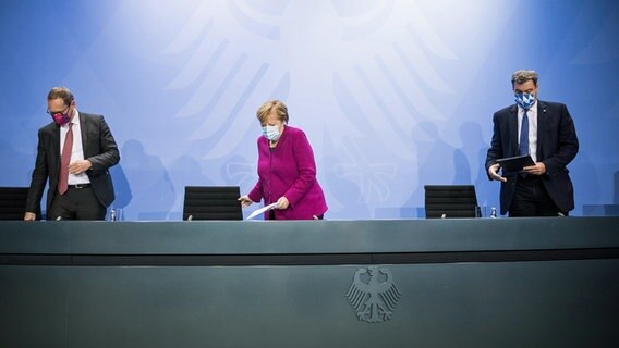 Vor einer Pressekonferenz nehmen Michael Müller, Angela Merkel und Markus Söder mit Masken ihre Plätze ein © dpa/AFP POOL Foto: Stefanie Loos