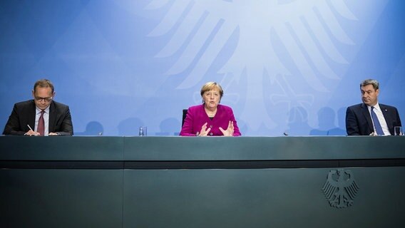 Bundeskanzlerin Angela Merkel (M.), Markus Söder (r., CSU), Ministerpräsident von Bayern, und Michael Müller (SPD), Regierender Bürgermeister von Berlin, sitzen bei einer Pressekonferenz nebeneinander. © dpa-Bildfunk/AFP POOL Foto: Stefanie Loos