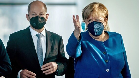 Angela Merkel geht neben Olaf Scholz (l.) und weist mit der Hand nach vorn. © dpa-Bildfunk 