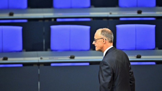 Friedrich Merz läuft nach gescheiterter Kanzlerwahl mit deprimiertem Blick entlang leerer Stuhlreihen im Bundestag. © dpa Foto: Sebastian Gollnow