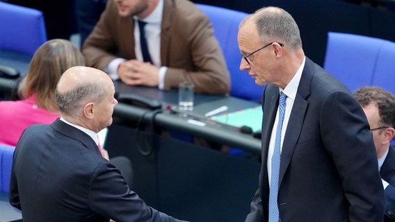 Der geschäftsführende Bundeskanzler Olaf Scholz (SPD, l) wünscht dem designierten Bundeskanzler Friedrich Merz (CDU) mit Bundestag beim zweiten Durchgang der Kanzlerwahl per Handschlag Glück. © dpa Foto: Kay Nietfeld