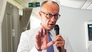 Bundeskanzler Friedrich Merz (CDU) spricht mit Journalisten im Flugzeug auf dem Weg vom BER nach Paris und Warschau. © picture alliance/dpa | Michael Kappeler Foto: Michael Kappeler