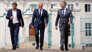 Robert Habeck (l-r, Grüne), Olaf Scholz (SPD) und Christian Lindner (FDP) auf dem Weg zur Abschlusspressekonferenz nach der Klausurtagung der Bundesregierung vor dem Schloss Meseberg. © Kay Nietfeld/dpa Pool/dpa 