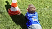 Bedrohlicher Schatten eines Erwachsenen fällt auf einen Jungen, der am Spielfeldrand sitzt (Bildmontage) © imago/blickwinkel 
