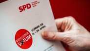 Eine Hand hält einen Musterbrief zum Mitgliedervotum der SPD zum Koalitionsvertrag. © dpa Foto: Michael Kappeler