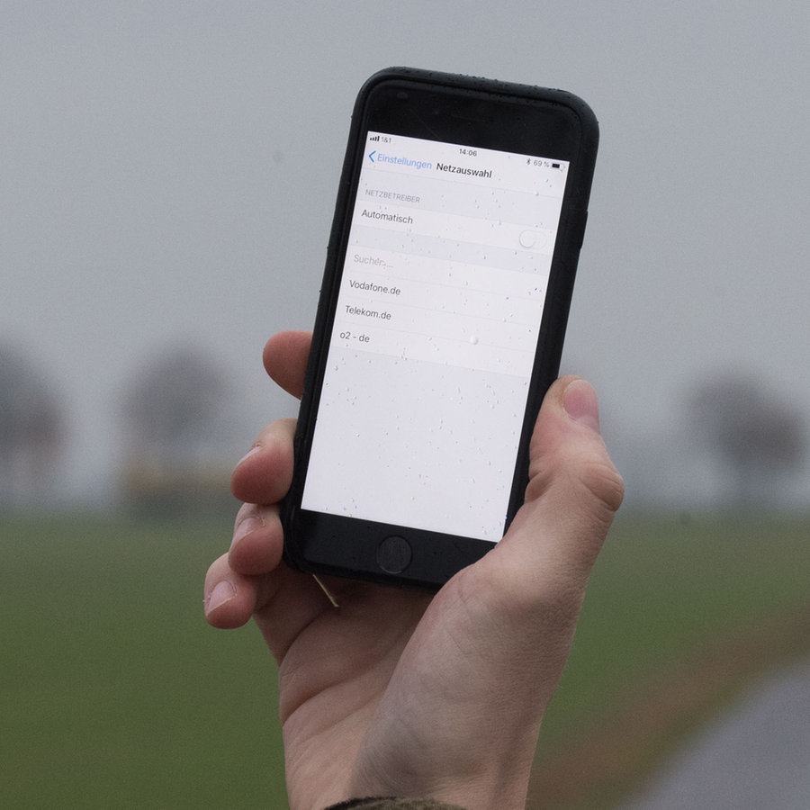 Ein Mann lässt in der Region Hannover auf einem Feldweg sein Smartphone nach Netzbetreibern suchen © picture alliance/dpa Foto: Julian Stratenschulte