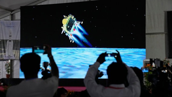 Journalisten filmen im indischen Bengaluru die Live-Übertragung der Landung des Raumschiffs "Chandrayaan-3" auf dem Mond. © Aijaz Rahi/AP/dpa Foto: Aijaz Rahi/AP/dpa