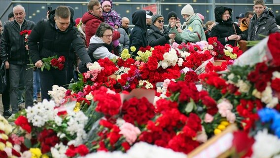 Menschen legen Blumen und Spielzeug am Zaun neben dem Konzertsaal bei Moskau ab, auf den am 22. März 2024 ein Terroranschlag verübt worden war. © Vitaly Smolnikov/AP/dpa 