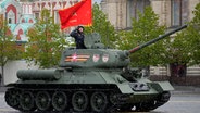 Ein legendärer sowjetischer T-34-Panzer mit roter Flagge während einer Militärparade in Moskau. © picture alliance/dpa/AP Foto: Alexander Zemlianichenko