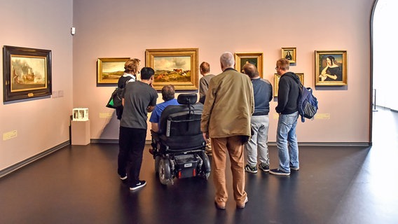 Mehrere Menschen mit Behinderungen stehen in einem Museum. © NDR Foto: Heide Soltau