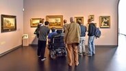 Mehrere Menschen mit Behinderungen stehen in einem Museum. © NDR Foto: Heide Soltau