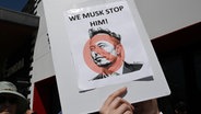Auf einer Demonstration gegen Elon Musk / Tesla in den USA hält ein Protestant ein Schild mit der Aufschrift "WE MUSK STOP HIM!" hoch © picture alliance / Anadolu Foto: Tayfun Coskun