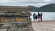 Menschen stehen am Ufer des Sees Loch Ness in Schottland © Benedikt von Imhoff/dpa Foto: Benedikt von Imhoff/dpa