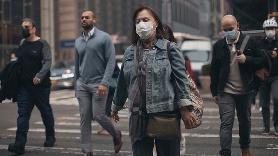 Menschen in New York überqueren eine Straße und tragen Masken wegen der Luftverschmutzung durch die Waldbrände in Kanada. © AP/dpa Foto: Andres Kudacki